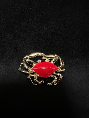 a gold ring with a red crab on it