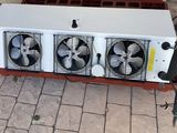 une photo d'un radiateur à trois ventilateurs posé sur un sol en briques