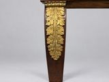 an antique wooden table with a gold leaf decoration on top of it