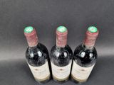 three bottles of red wine are lined up on a black surface
