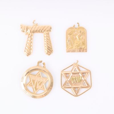 trois pendentifs en or de formes et de tailles différentes sur un fond blanc
