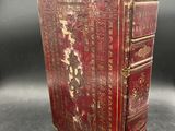 an old red book sitting on top of a table