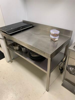 un ordinateur portable posé sur une table de cuisine, sur laquelle se trouvent des casseroles et des poêles