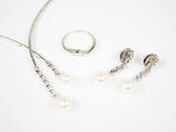 un collier, un bracelet et une bague posés sur un fond blanc