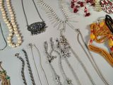 many different types of necklaces and bracelets laid out on a table