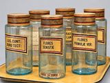 four glass jars with labels are on a tray with a wooden tray