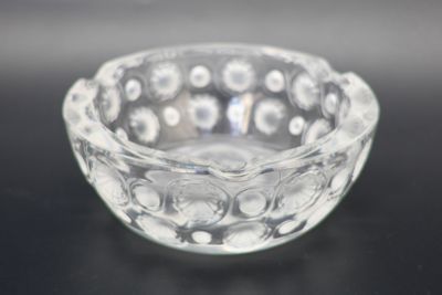 a small glass bowl on a table with a black background