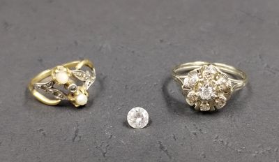 two gold rings and a diamond ring on a table next to a coin