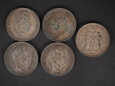quatre vieilles pièces de monnaie sont posées sur une table devant un fond noir