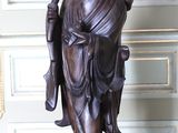 une statue représentant une personne tenant un éventail, posée sur une table rouge