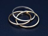 a close up of three gold rings sitting on top of a black surface