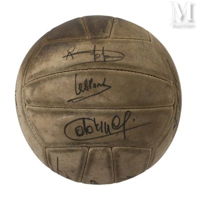 un vieux ballon de foot couvert d'autographes, posé sur une surface blanche