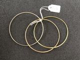 three gold hoop earrings on a black surface with a price tag