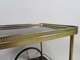 a gold bar cart with a glass top and wheels