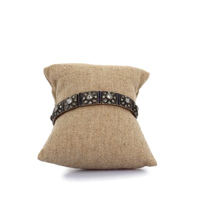 un oreiller marron orné d'une ceinture en cuir noir, sur fond blanc