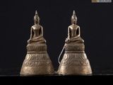 une paire de statues de Bouddha en laiton posées sur une surface noire