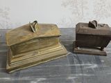 une paire de serre-livres anciens en laiton posés sur une table, avec un fond tapissé