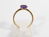 a close up of a gold ring with a purple stone