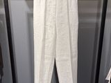 une photo d'un pantalon blanc suspendu à un portant