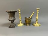 three antique brass candlesticks and a mortar set on a grey background
