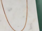 un collier à chaîne en or posé sur une dalle de marbre