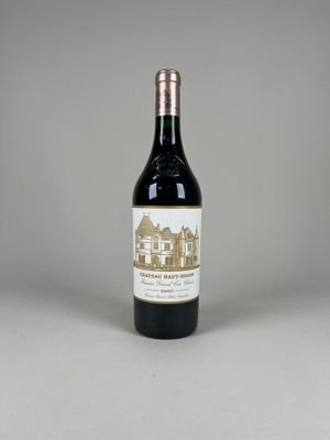 La bouteille de vin est posée sur la table, devant un fond gris.