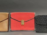 three different colors of purses are lined up on a table