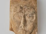 une tête d'homme sculptée dans la pierre, avec une croix sur le front