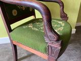 a wooden chair with a green upholstered seat and arm rest