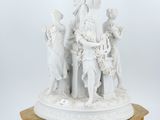 une statue blanche représentant une femme et deux enfants, posée sur un socle