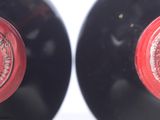 two bottles of red wine sitting next to each other on top of a table