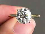 un gros plan sur la main d'une personne tenant une bague en diamant