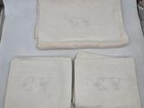 trois serviettes blanches ornées de monogrammes, posées sur une table