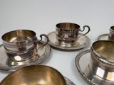 four silver cups and saucers sitting on a table