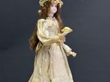 an antique doll is standing on top of a suitcase with a hat on