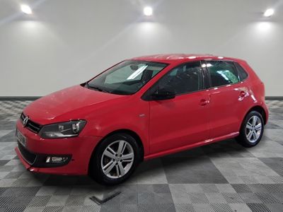 Une Volkswagen Golf rouge est garée dans une pièce dont le sol est à carreaux.