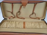 a tan suitcase with a brown handle and a brown strap