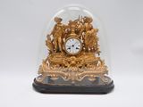 une horloge en or sous un dôme de verre sur une table