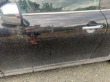 a black car with a broken door is parked on the side of the road