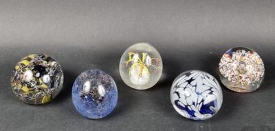 six glass marbles are lined up on a black surface