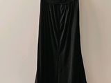 une robe noire sur un cintre, près d'un mur blanc