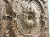 a carved wood panel with a face on it