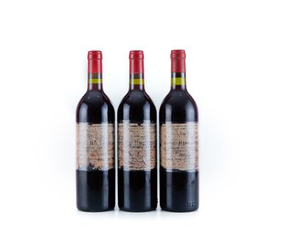 trois bouteilles de vin rouge posées l'une à côté de l'autre sur une surface blanche