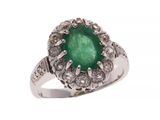 gros plan d'une bague avec une pierre verte entourée de diamants
