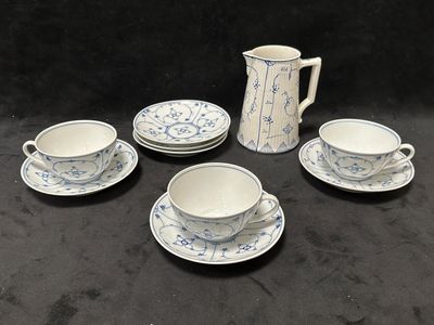 cinq tasses et soucoupes posées sur une table, avec un pichet
