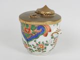 un petit vase avec un couvercle posé sur une surface blanche