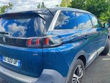 a blue car parked in a parking lot with trees in the background