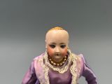 a doll that is wearing a purple dress and pearls