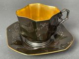 black and gold tea cup and saucer with a gold rim