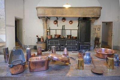de nombreuses casseroles et poêles en cuivre posées sur une table